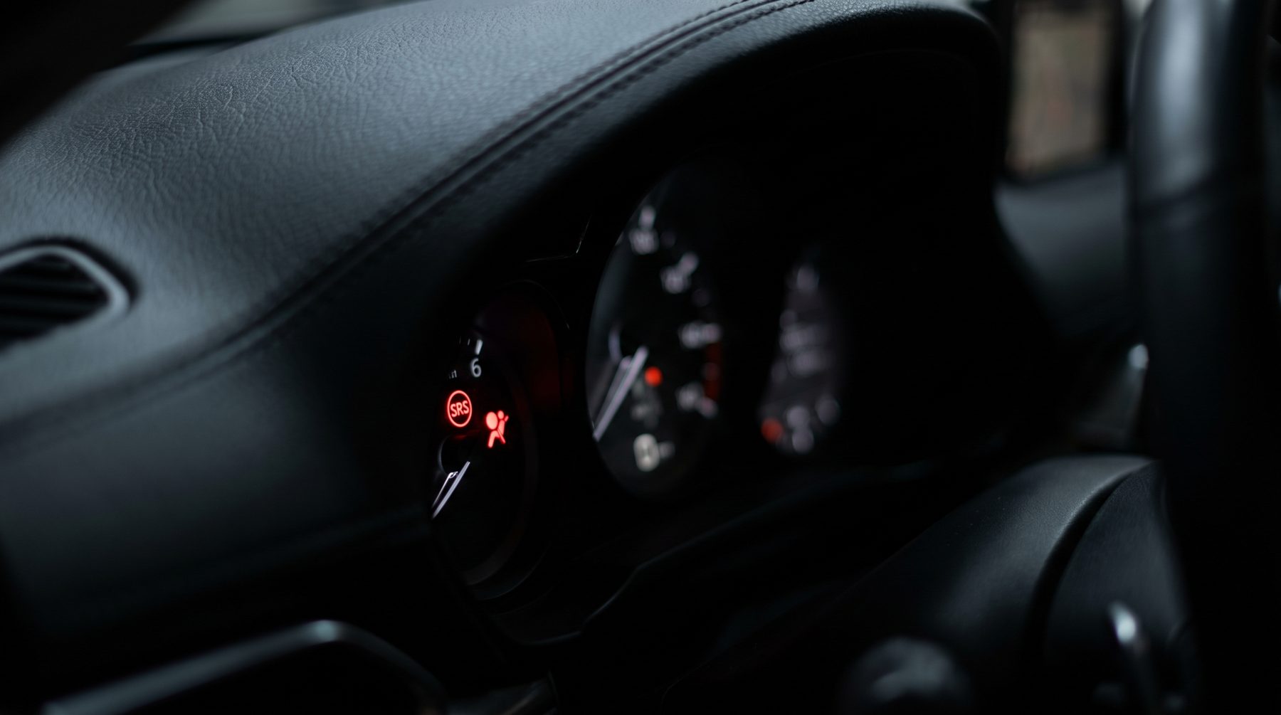 Red airbag SRS warning light glowing on a car dashboard