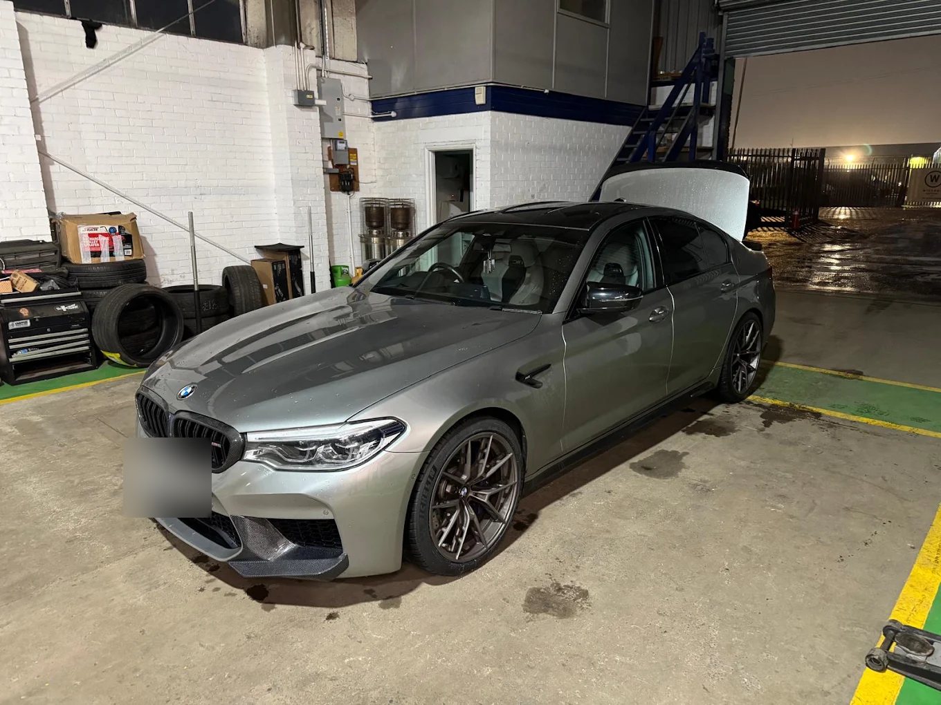 Grey BMW M5 Competition in the Liam's Tyres workshop bay