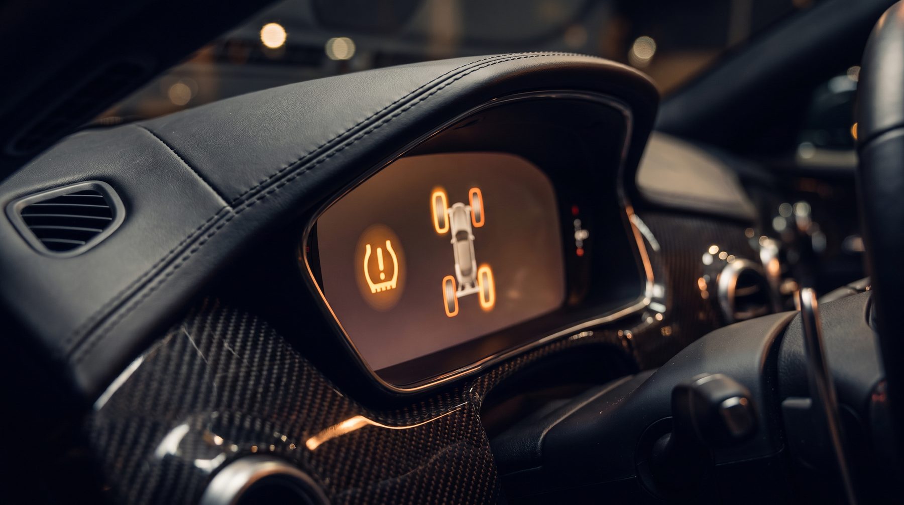 Tyre pressure monitoring warning light glowing on a premium car dashboard